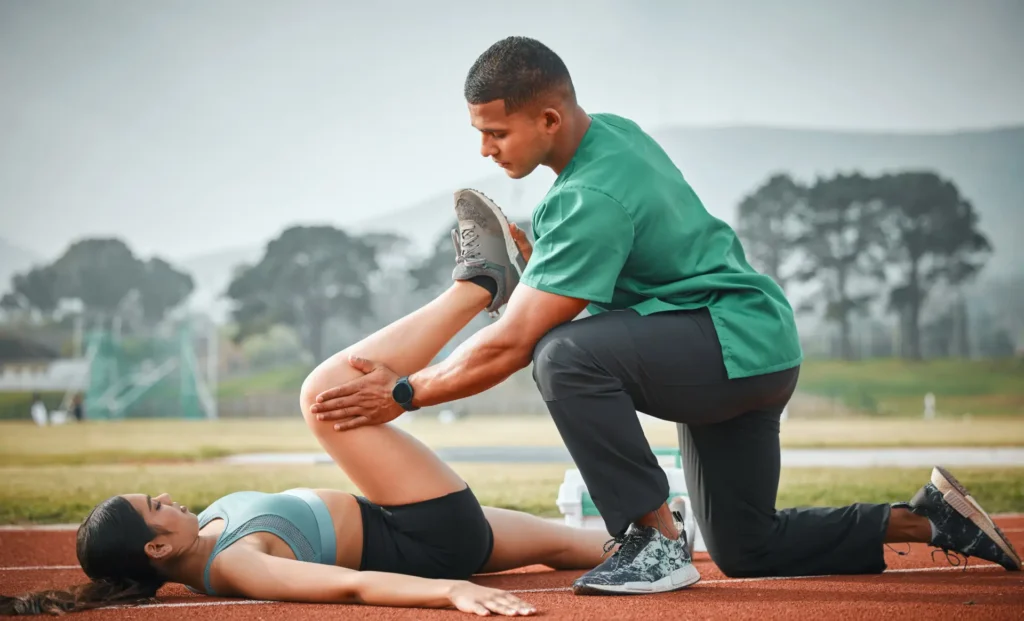 man-assisting-woman-with-leg-stretching-on-track