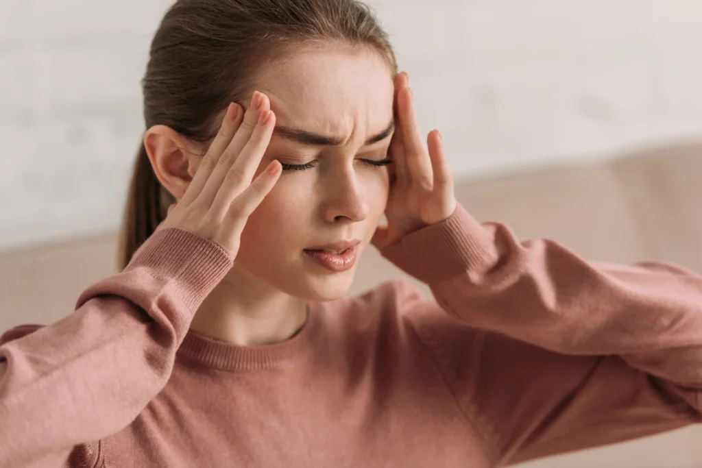 woman with headache massaging temples indoors 2026 03 12 23 50 19 utc